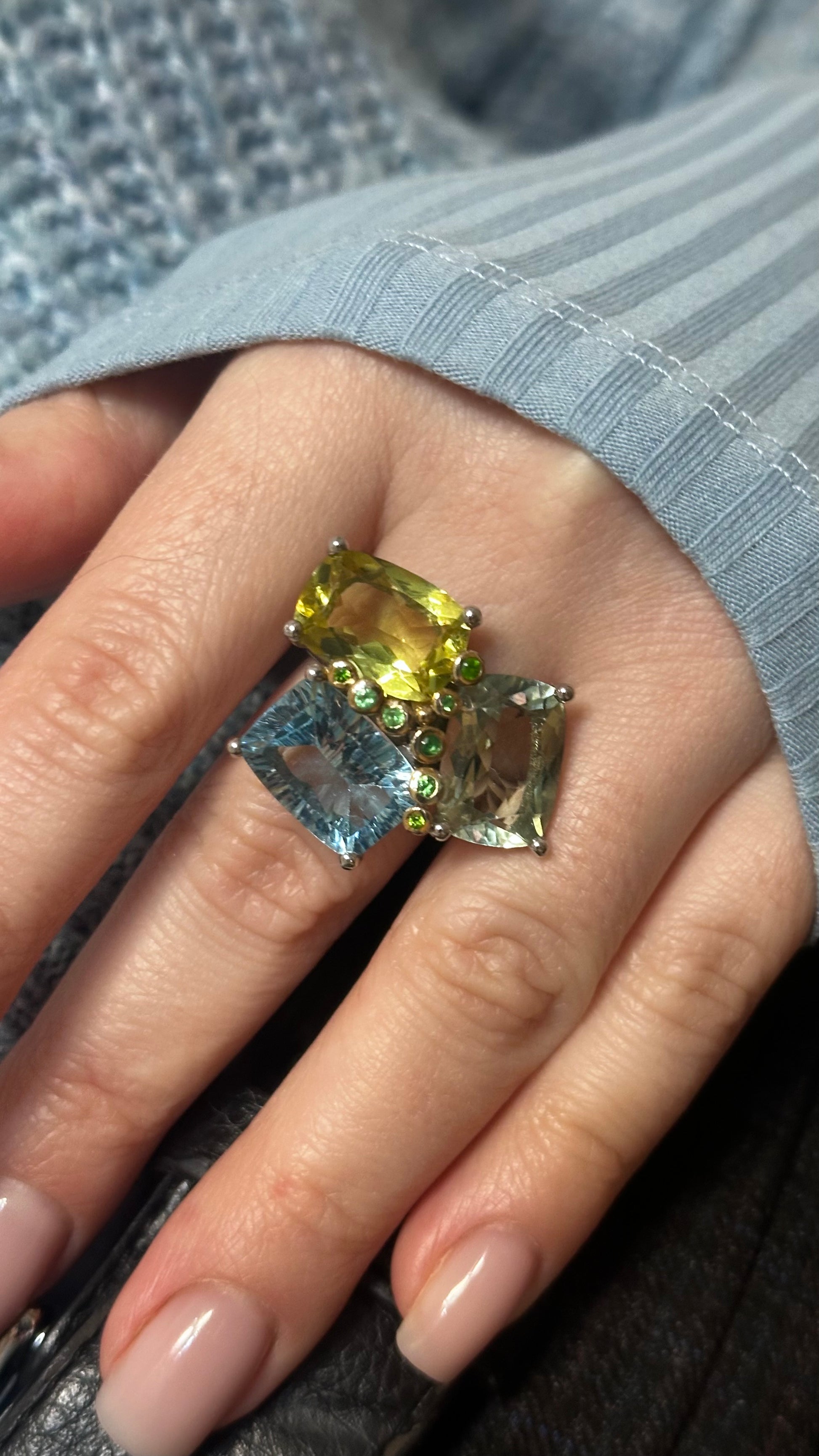 Close-up of a hand wearing a ring with multicolored gemstones.